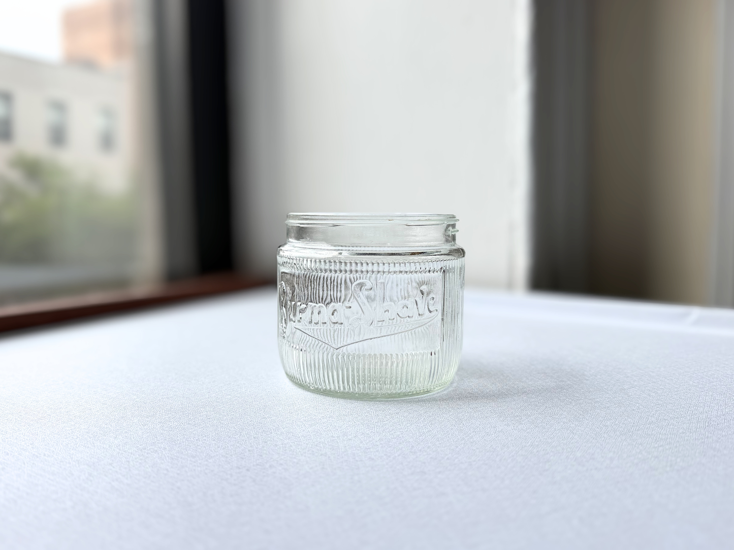 Side view of a vintage ribbed glass Burma-Shave jar showing its full silhouette and textured surface, suited for an apothecary shelf display.