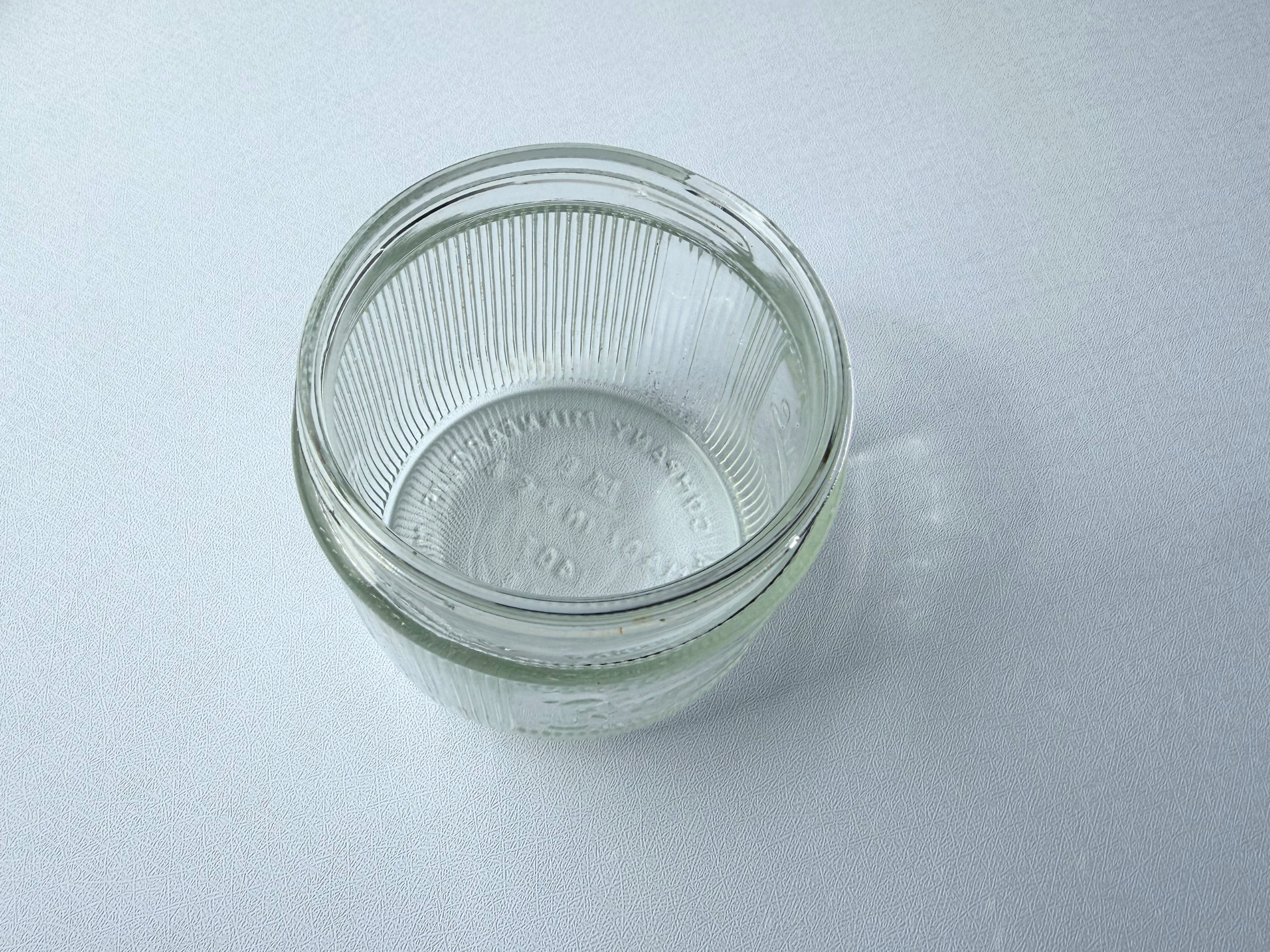 Top-down view of a vintage ribbed glass Burma-Shave jar, showing the wide mouth opening from above.