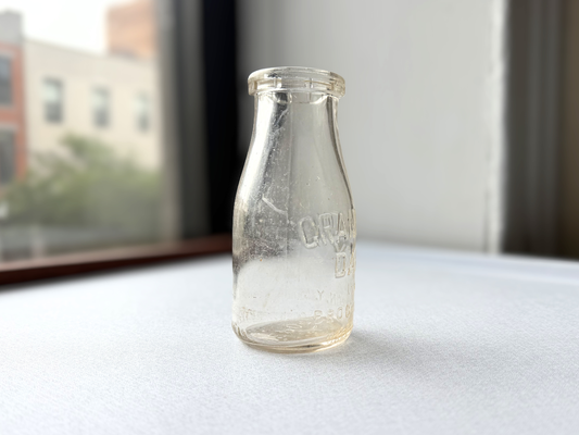 Vintage clear glass Grandview Dairy half-pint milk bottle from Brooklyn, NY, shown at a three-quarter angle highlighting its compact, tidy mid-century dairy bottle shape.