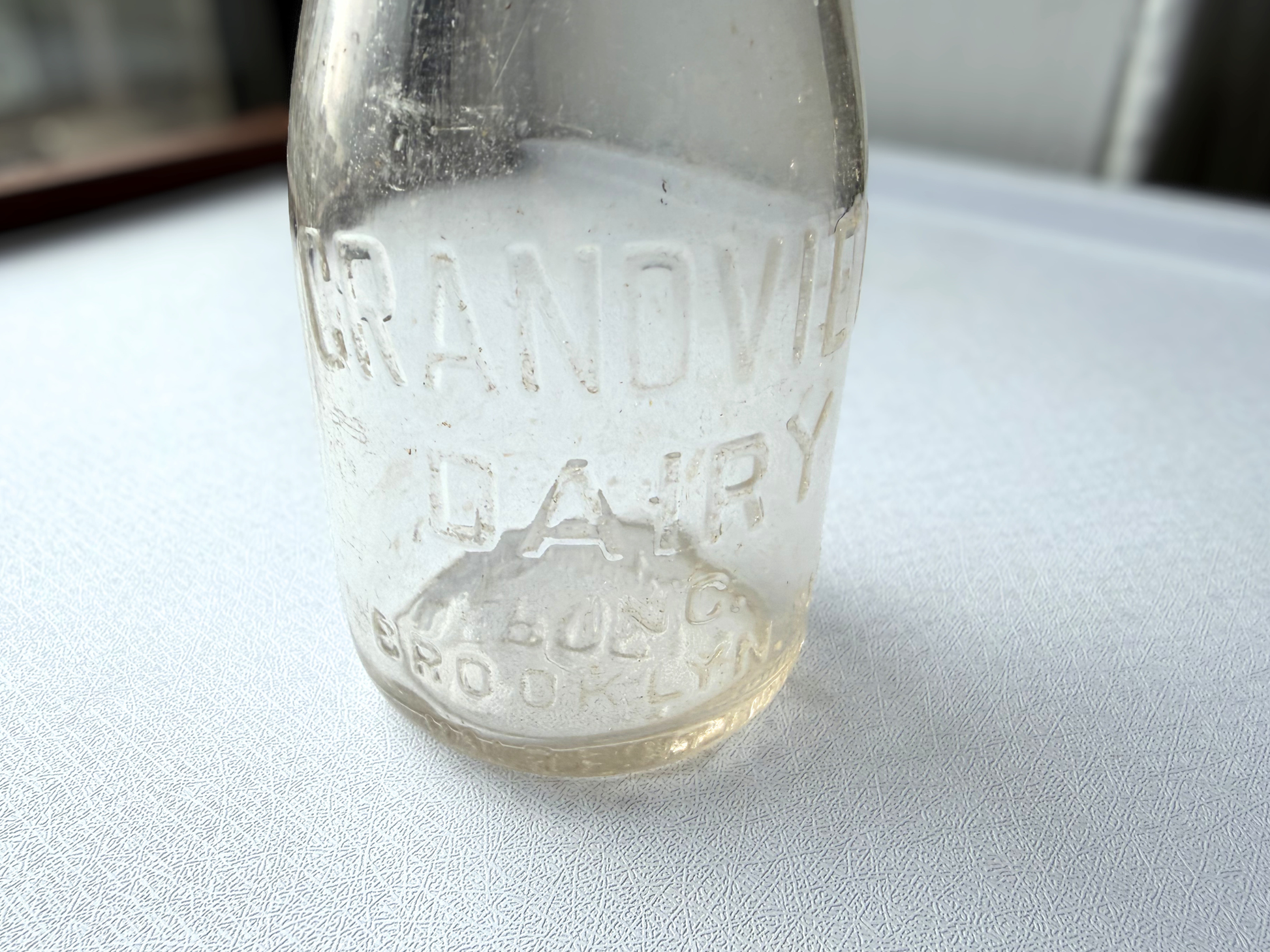 Close-up of the embossed lettering on the front of a vintage Grandview Dairy Inc. Brooklyn NY half pint milk bottle, showing crisp, legible mid-century dairy branding.