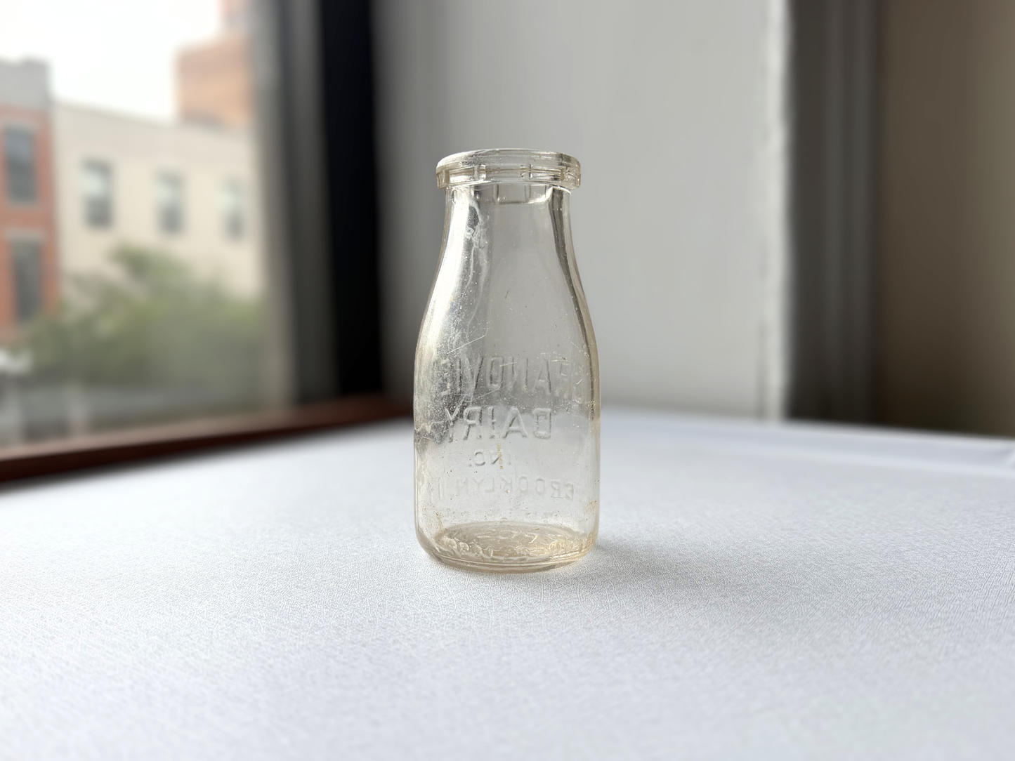Side view of a vintage clear glass Grandview Dairy half-pint milk bottle showing its full silhouette, suited for farmhouse or cottagecore shelf styling.