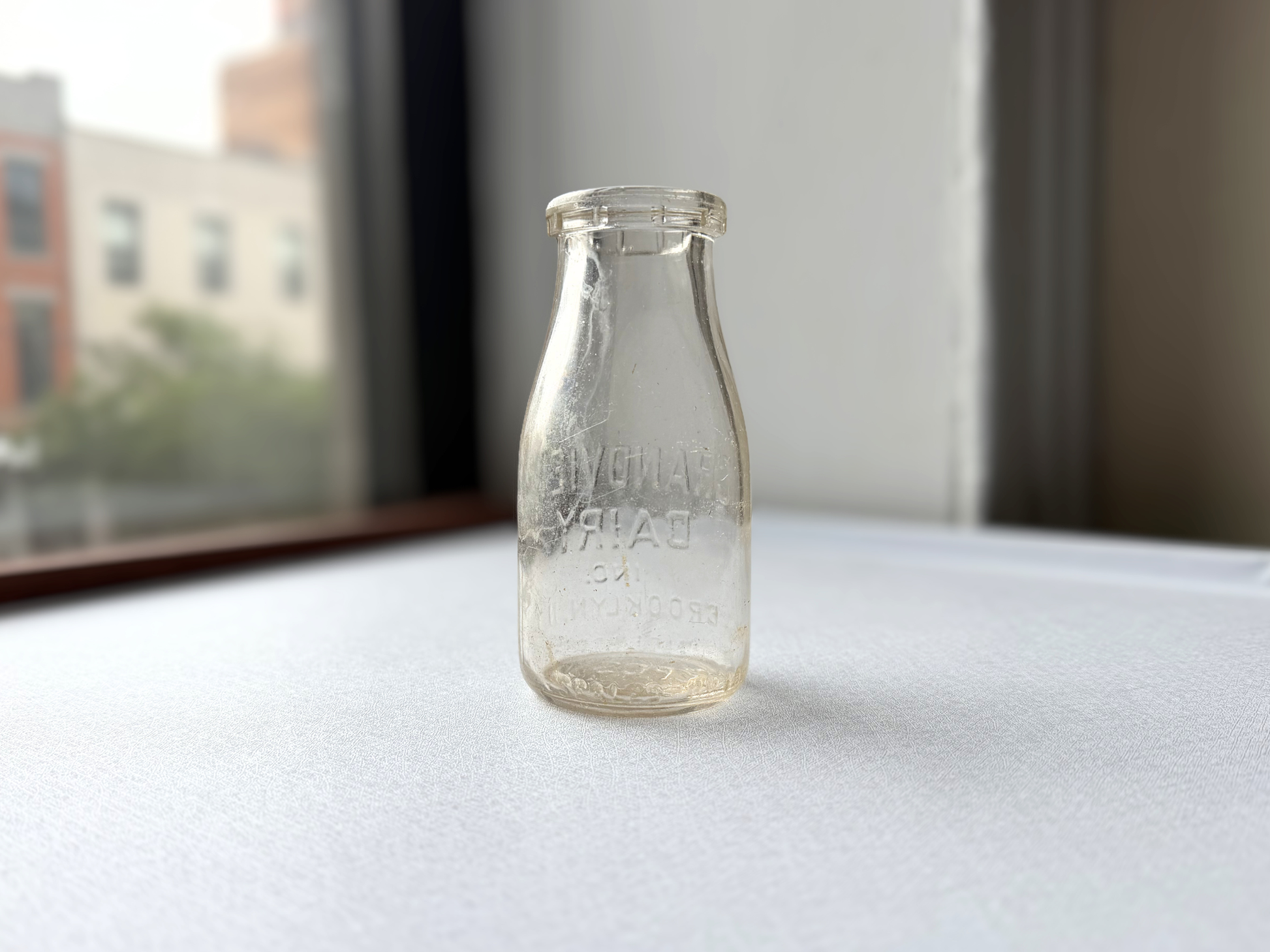 Side view of a vintage clear glass Grandview Dairy half-pint milk bottle showing its full silhouette, suited for farmhouse or cottagecore shelf styling.