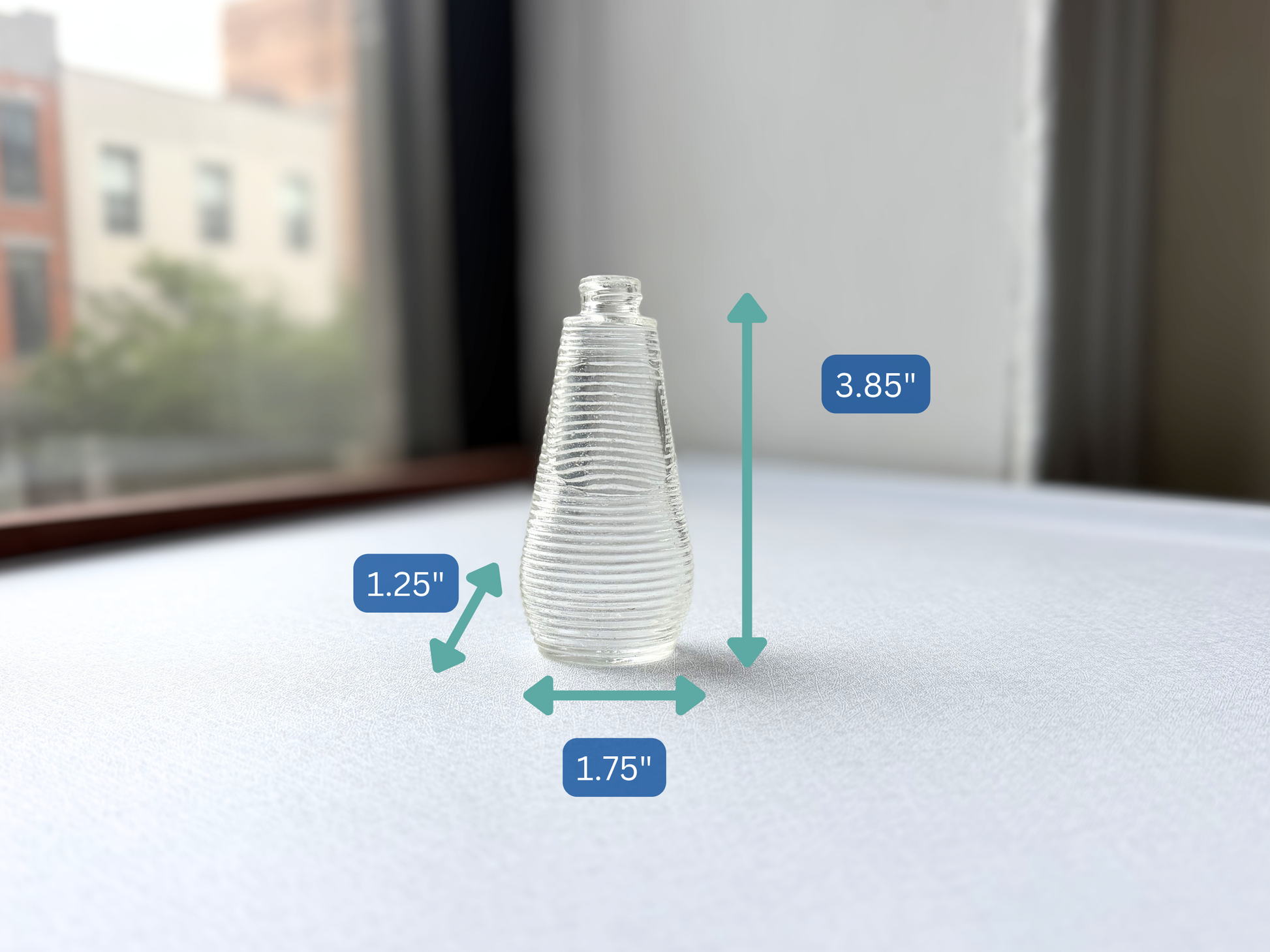 Small vintage ribbed glass halo bottle shown with measurement markers indicating a height of 3.85 inches, width of 1.75 inches, and depth of 1.25 inches, illustrating its miniature scale.