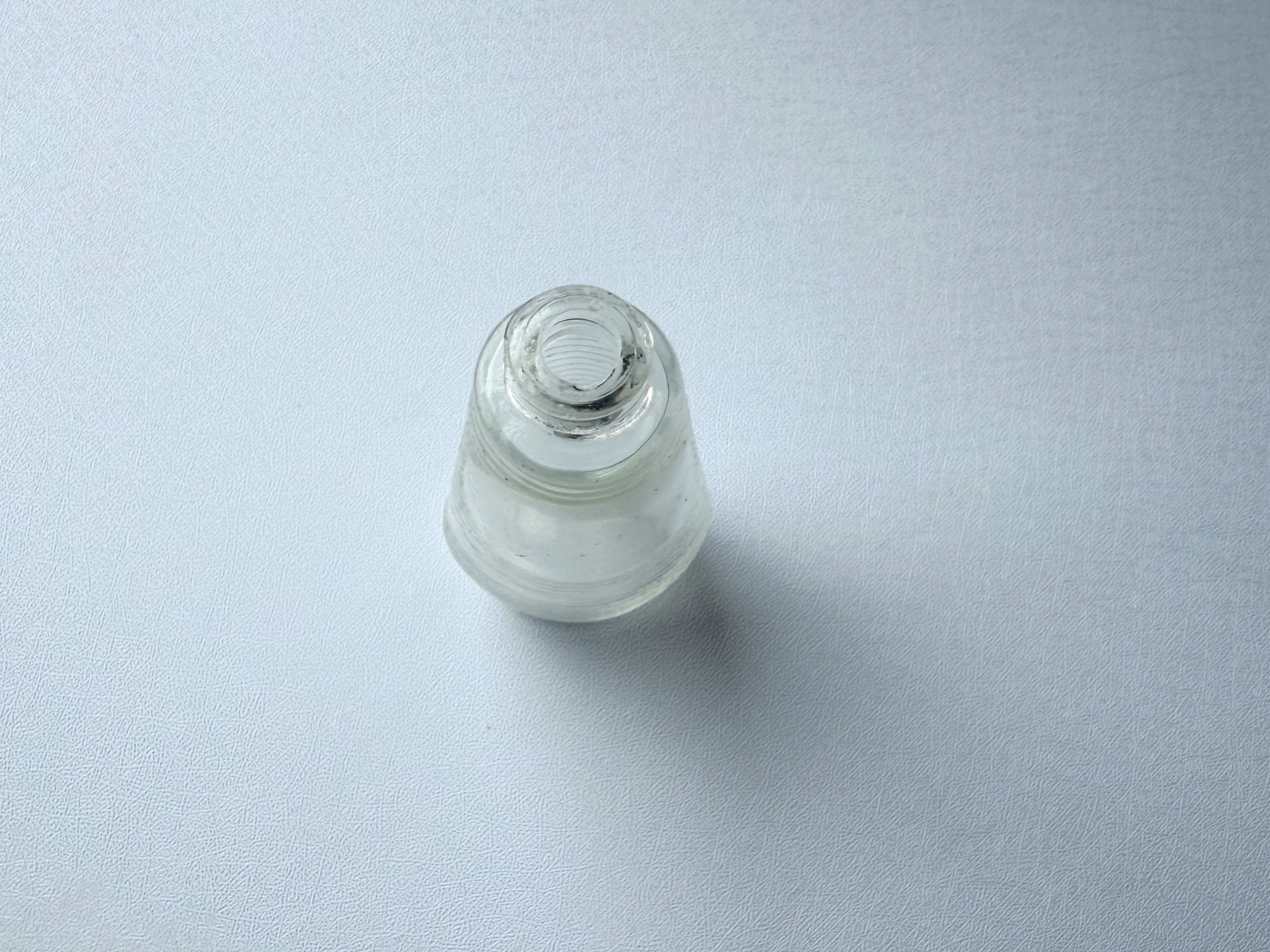 Top-down view of a small vintage ribbed glass halo bottle, showing the narrow neck opening and rounded shoulder from above.