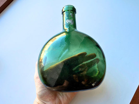Vintage olive green onion bottle angled view showing globular body and short neck, pre-automation glass