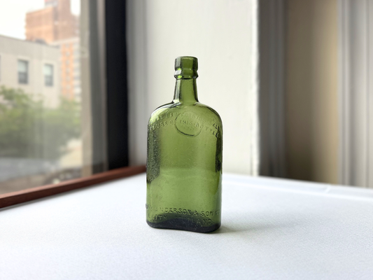 Front view of a vintage deep green glass bottle embossed William Sanderson & Son Ltd. Leith Scotland, showing its rounded silhouette and rich green color, ideal for bar cart or vintage entertaining styling.