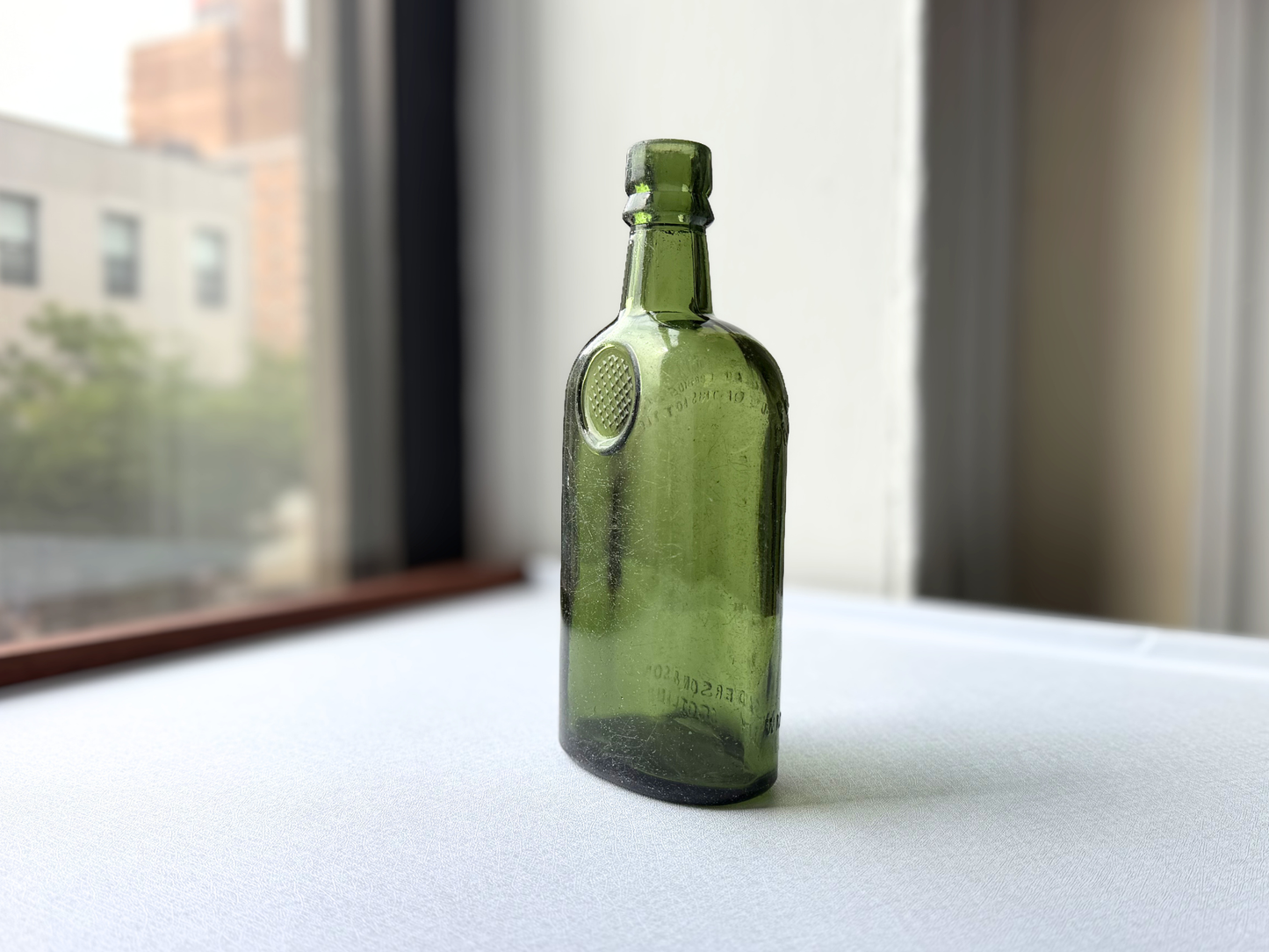 Side view of a vintage deep green glass Sanderson bottle showing its full silhouette and gentle surface texture, suited for bar cart or open shelf display.